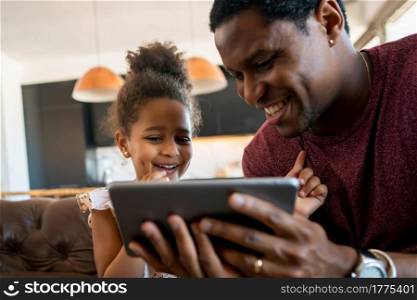 Portrait of a daughter and father using a digital tablet while staying at home. Monoparental concept.
