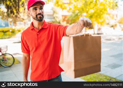 Portrait of a delivery man carrying packages while making home delivery to his customer. Delivery and shipping concept.