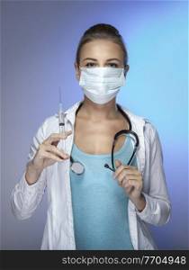 Portrait of a Doctor Wearing Mask with Syringe in Hand isolated on Blue Background. Beauty Treatment. Injection of Beauty. Women&rsquo;s Beauty.. Doctor with a Syrigne