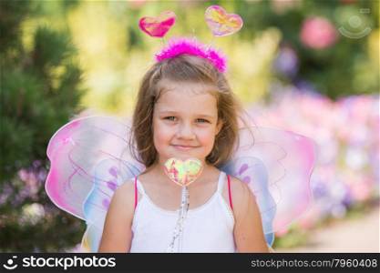 Portrait of a fairy with a magic wand. happy four-year-girl in a fairy dress with wings on his back and antennae on his head