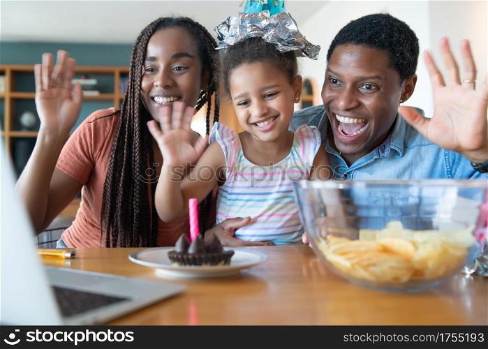 Portrait of a family celebrating birthday online on a video call while staying at home. New normal lifestyle concept.