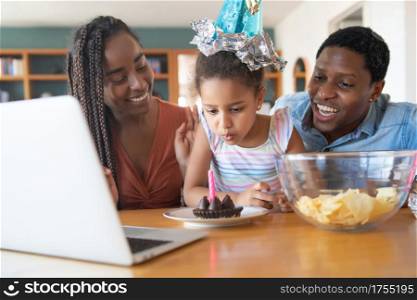 Portrait of a family celebrating birthday online on a video call with laptop while staying at home. New normal lifestyle concept.
