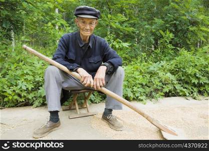 Portrait of a farmer sitting on a stool in a field, Zhigou, Shandong Province, China