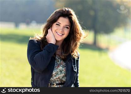 Portrait of a fashionable and lovely woman with nice hairstyle posing outdoor on a sunny day