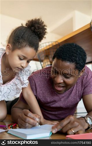Portrait of a father and daughter spending time together and drawing on the floor while staying at home. New normal lifestyle concept.