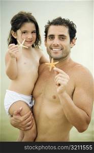 Portrait of a father and his daughter holding a starfish