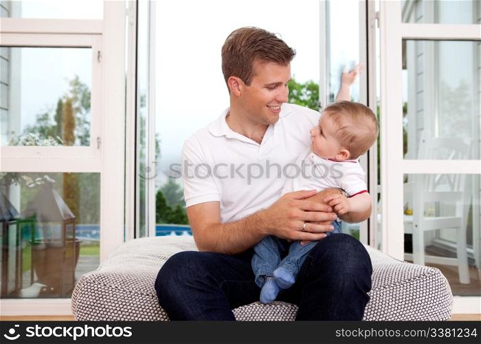 Portrait of a father and son smiling, looking at each other in a home interior