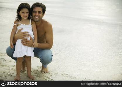 Portrait of a father holding his daughter on the beach