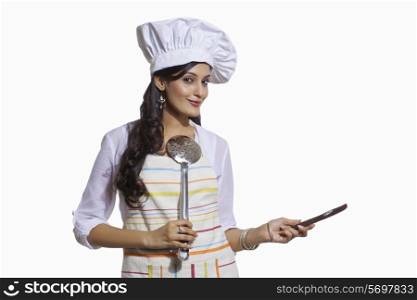 Portrait of a female chef with cooking utensils