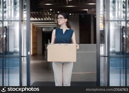 portrait of a female company employee standing outdoor with box of stuff. Leaving business. Female office worker lost her job.Job loss due to COVID-19 virus pandemic concept
