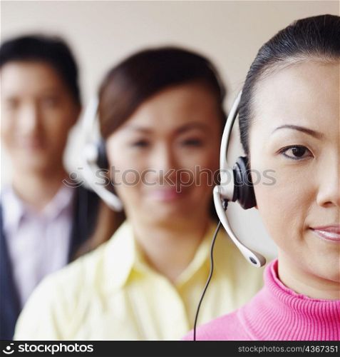 Portrait of a female customer service representative with two colleagues in the background