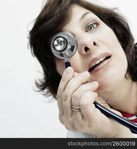 Portrait of a female doctor covering her eye with a stethoscope