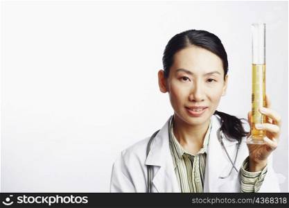 Portrait of a female doctor holding a graduated cylinder and smiling