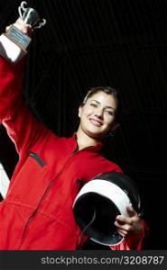 Portrait of a female go-cart racer holding a trophy with her hand raised and smiling