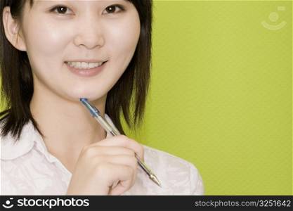 Portrait of a female office worker holding a pen and smiling