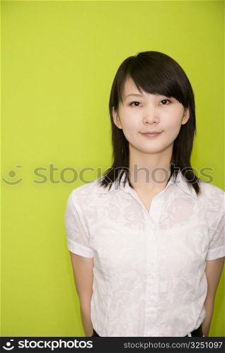 Portrait of a female office worker smiling with her hands behind her back