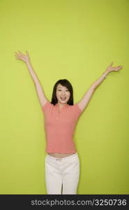 Portrait of a female office worker standing with her arms raised and smiling