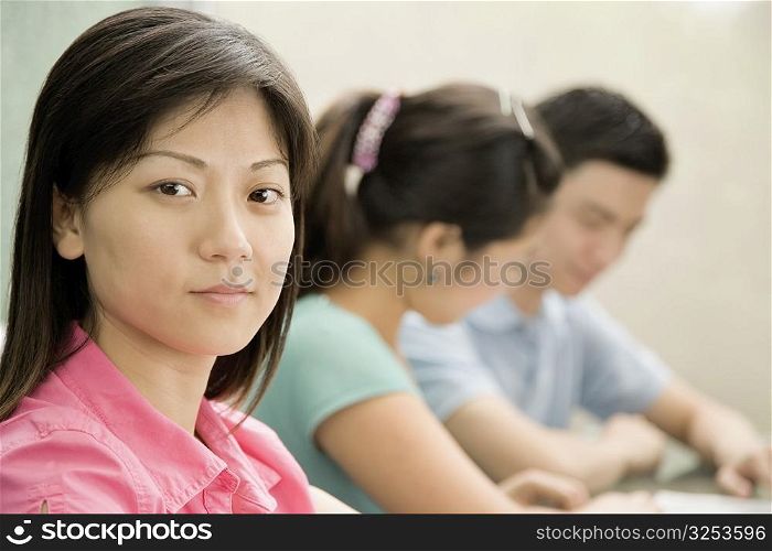Portrait of a female office worker with two other office workers sitting beside her