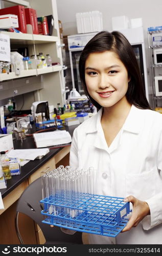 Portrait of a female pharmacist holding test tubes on a rack
