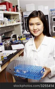Portrait of a female pharmacist holding test tubes on a rack