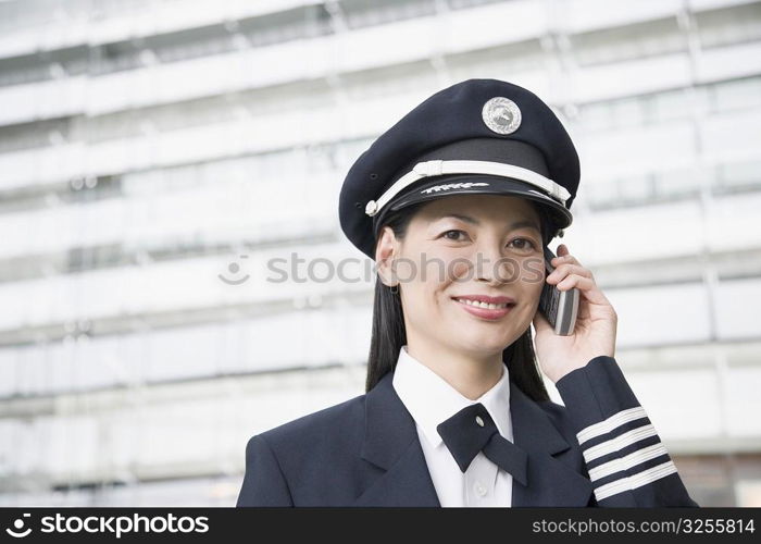 Portrait of a female pilot talking on a mobile phone and smiling