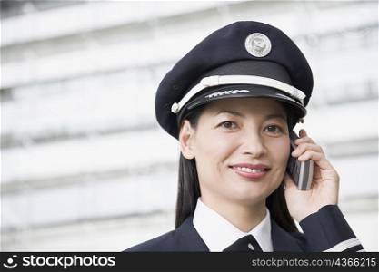 Portrait of a female pilot talking on a mobile phone and smiling