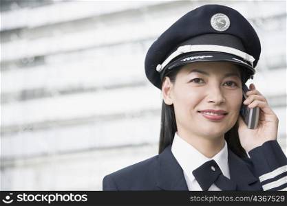 Portrait of a female pilot talking on a mobile phone and smiling