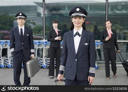 Portrait of a female pilot with a pilot and two cabin crews standing in the background