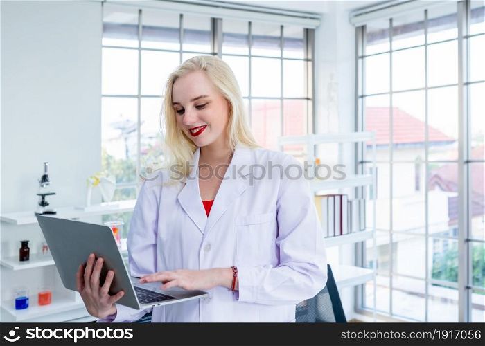 portrait of a female researcher carrying working with laptop computer and out research in a chemistry lab scientist holding test tube with sample in Laboratory analysis background