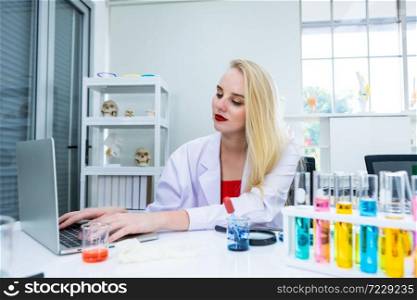 portrait of a female researcher carrying working with laptop computer and out research in a chemistry lab scientist holding test tube with sample in Laboratory analysis background