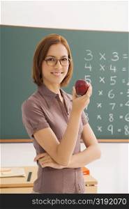 Portrait of a female teacher holding an apple and smiling