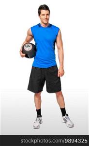 Portrait of a fit young white male athlete with short dark hair posing by himself holding a black medicine ball in a studio with a white background wearing black shorts   a blue sleeveless shirt.