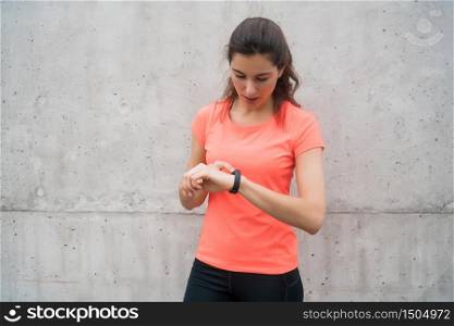 Portrait of a fitness woman checking time on her smart watch. Sport and healthy lifestyle concept.