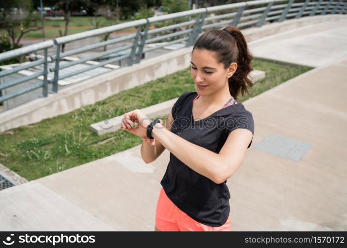 Portrait of a fitness woman checking time on her smart watch. Sport and healthy lifestyle concept.