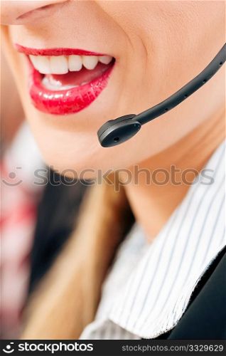 Portrait of a friendly female call center operator (only parts of face) rendering customer service