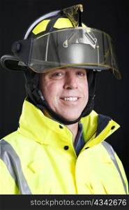 Portrait of a friendly, smiling fire fighter on black background.