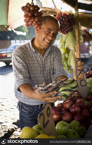 Portrait of a fruit seller holding apples in a plastic bag, Santo Domingo, Dominican Republic