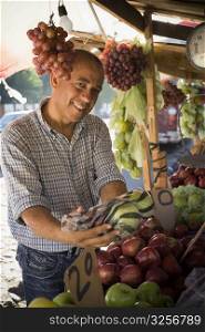 Portrait of a fruit seller holding apples in a plastic bag, Santo Domingo, Dominican Republic