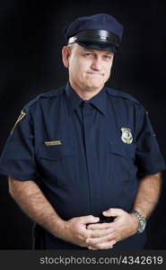 Portrait of a frustrated police officer, photographed against a black background.