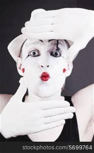 Portrait of a funny mime in white hat on a black background