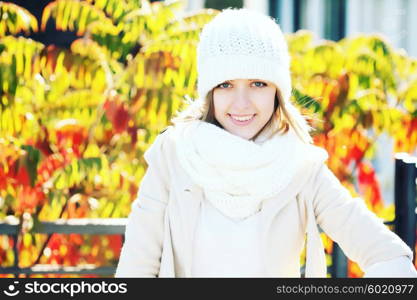 Portrait of a funny young girl in the autumn weather in warm clothes, scarf and hat. Young woman in forest in fall colors.