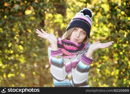 Portrait of a funny young girl in the autumn weather in warm clothes, scarf and hat. Young woman in forest in fall colors.