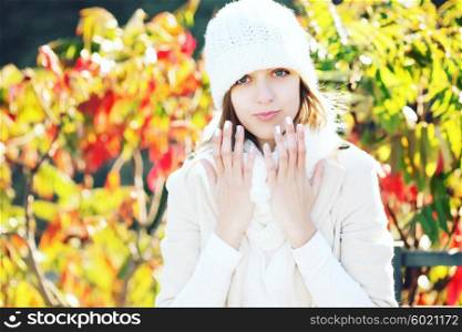 Portrait of a funny young girl in the autumn weather in warm clothes, scarf and hat. Young woman in forest in fall colors.