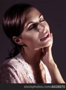 Portrait of a gentle nice female with closed eyes enjoying using cosmetics, isolated on black background, natural beauty