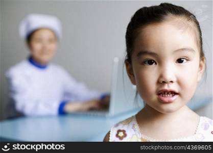 Portrait of a girl and a nurse working on a laptop in the background