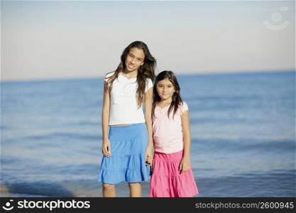Portrait of a girl and her sister standing on the beach