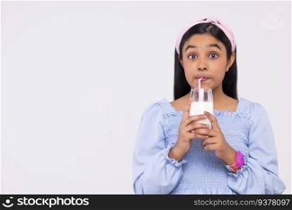 Portrait of a girl drinking milk against plain background