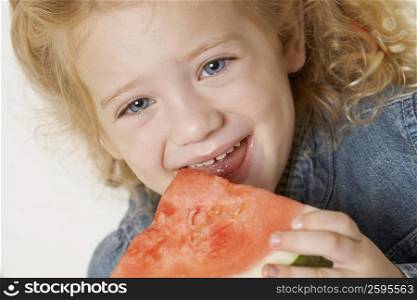 Portrait of a girl eating a slice of watermelon and smiling