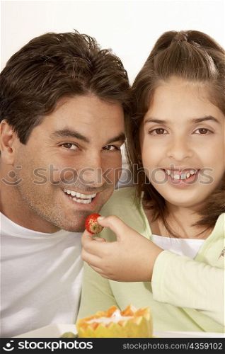 Portrait of a girl feeding her father a strawberry