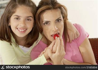 Portrait of a girl feeding her mother strawberries